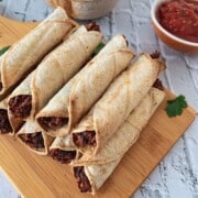 Rolled up black bean taquitos on a platter ready to eat.