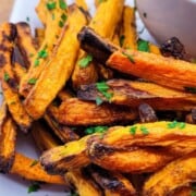 Carrots cut into strips piled on a plate with a dip.