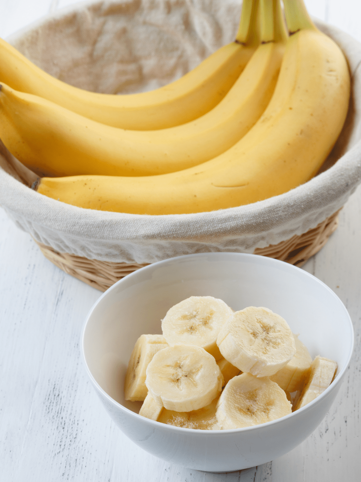 Bananas sliced in a bowl and  a bunch of bananas.