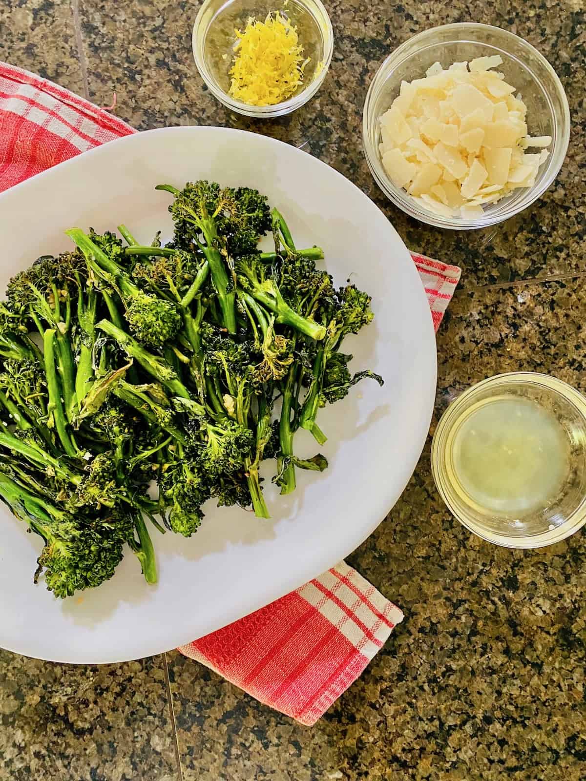 broccolini plated with bowls of shaved parmesan, lemon juice, and lemon zest on the side.
