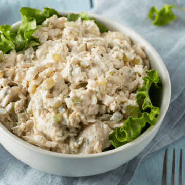 White bowl lined with lettuce and topped with chicken salad.
