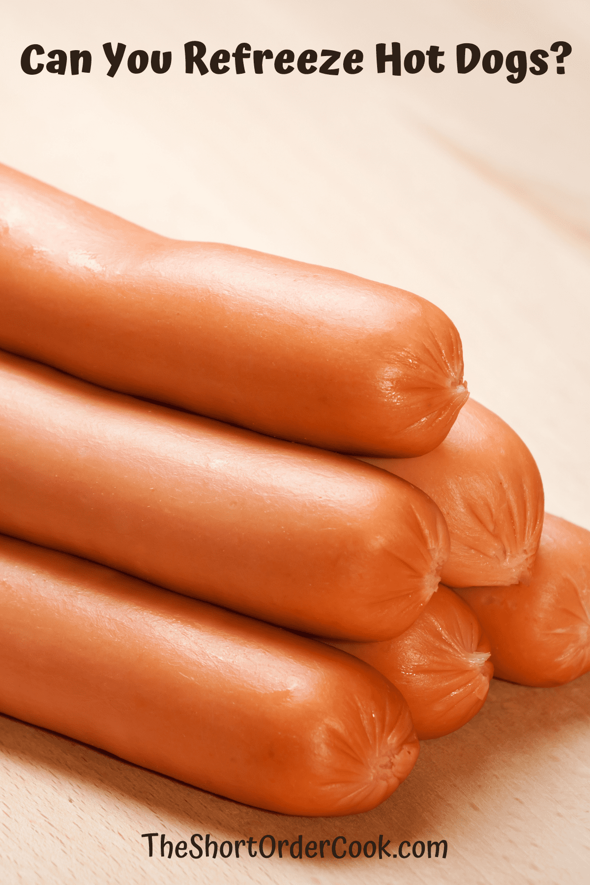 Uncooked hot dogs stacked on a cutting board.