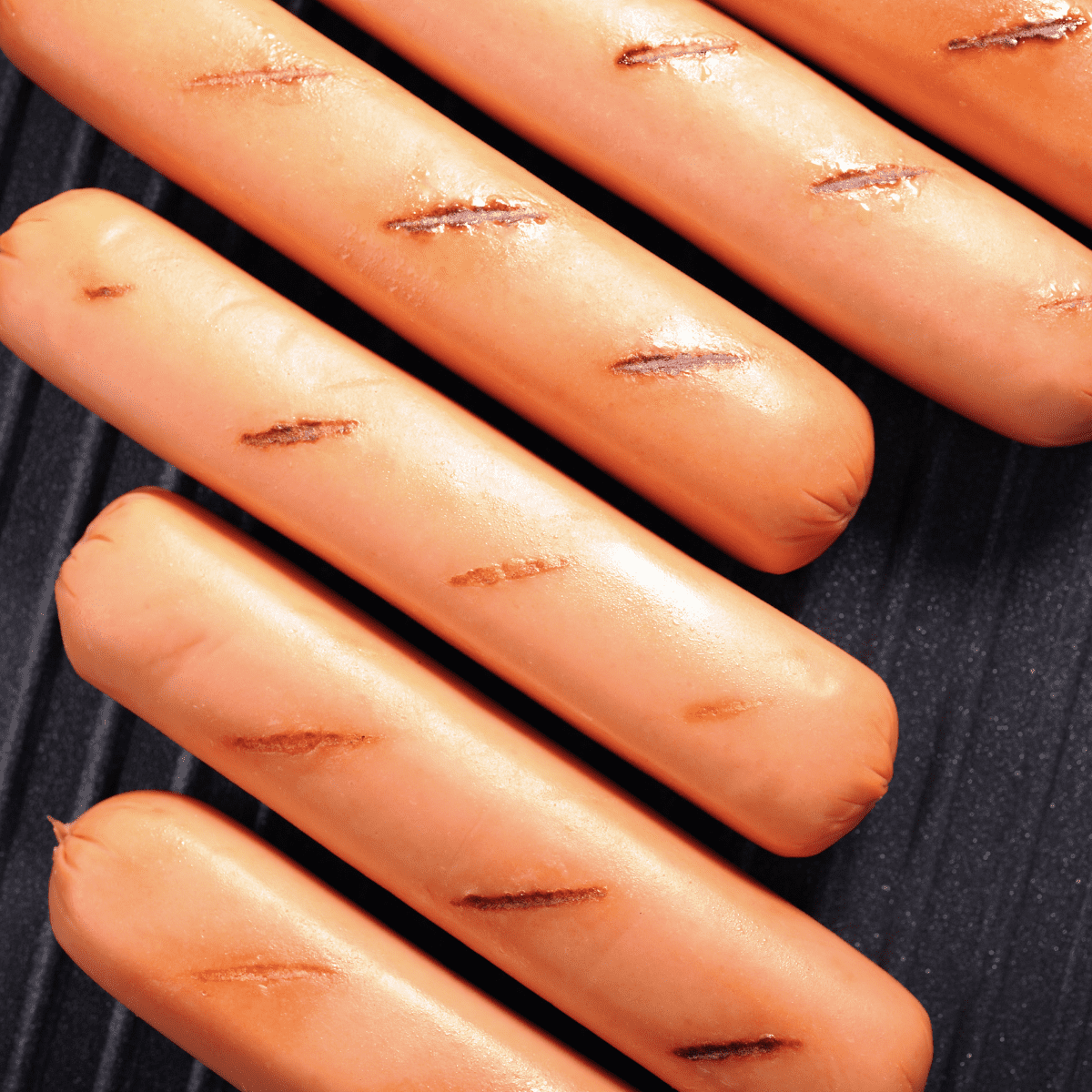 Hot dogs will grill marks cooking on a bbq.