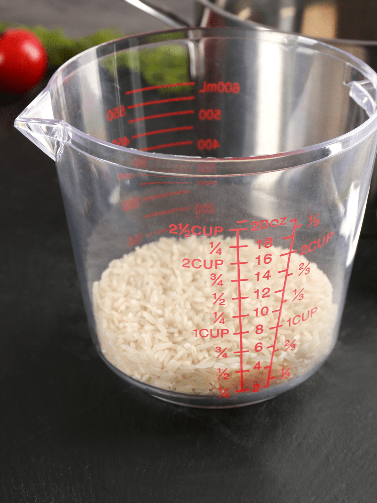 A glass measuring cup partially filled with grains of rice.