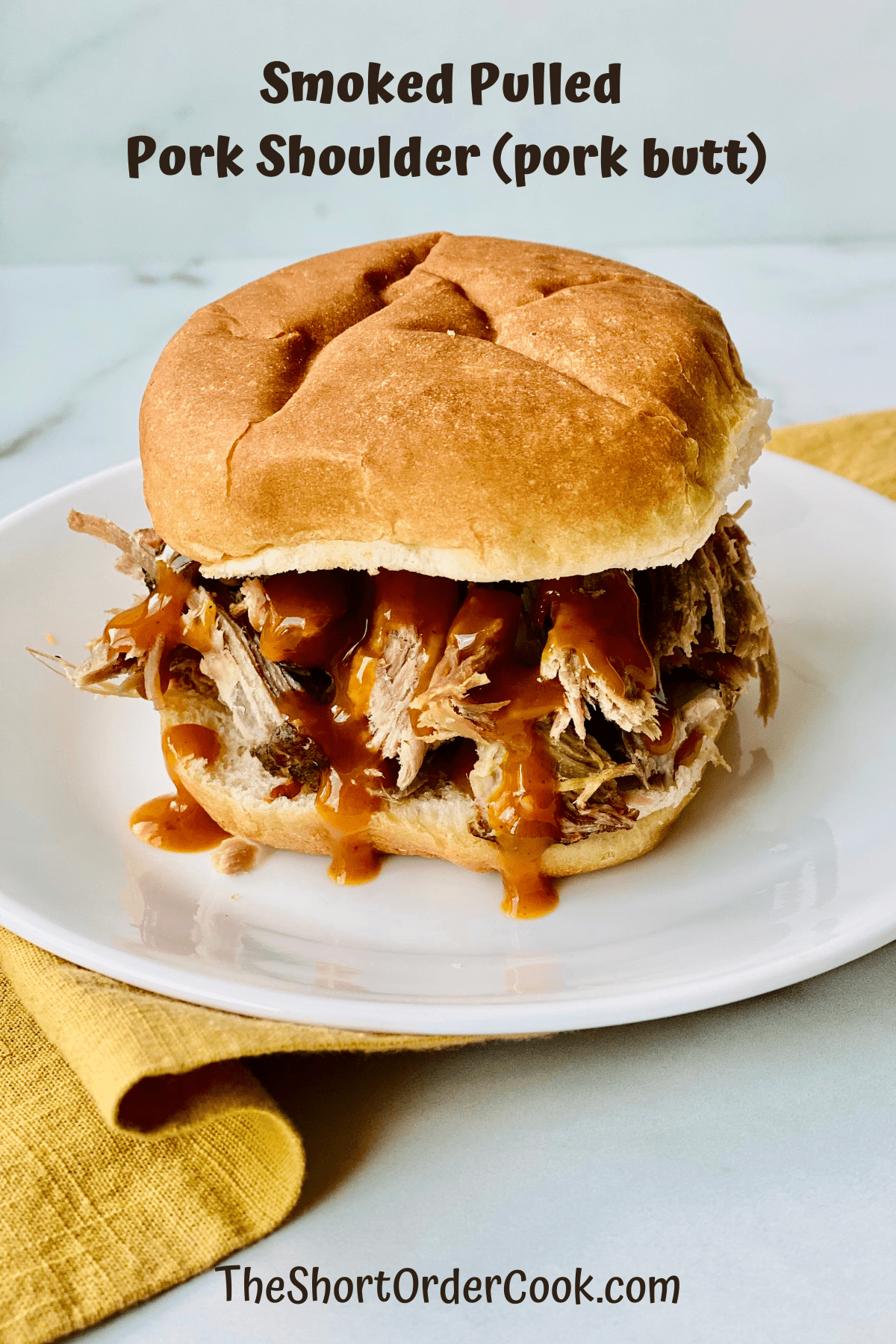 Smoked Pulled Pork Shoulder (pork butt) on a bun with bbq sauce.