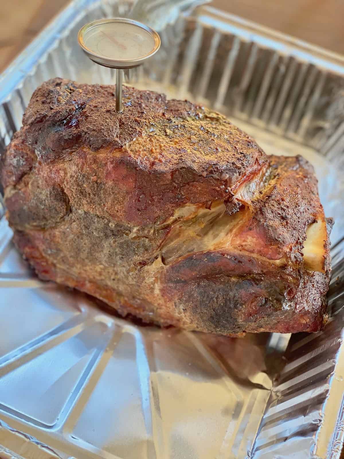 Smoked pork butt added to a foil pan.