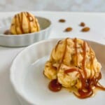 Two plated scoops of caramel swirl ice cream topped with caramel sauce.
