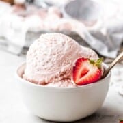 A bowl with strawberry ice cream and berry slices.
