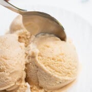 Closeup of a spoon digging into vanilla ice cream scoops.