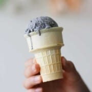Black sesame ice cream scooped and dripping down a cone.
