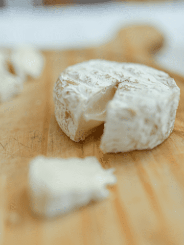 A wedge of brie on a cutting board.