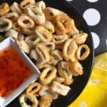 Plated air fried calamari rings with a dipping sauce.