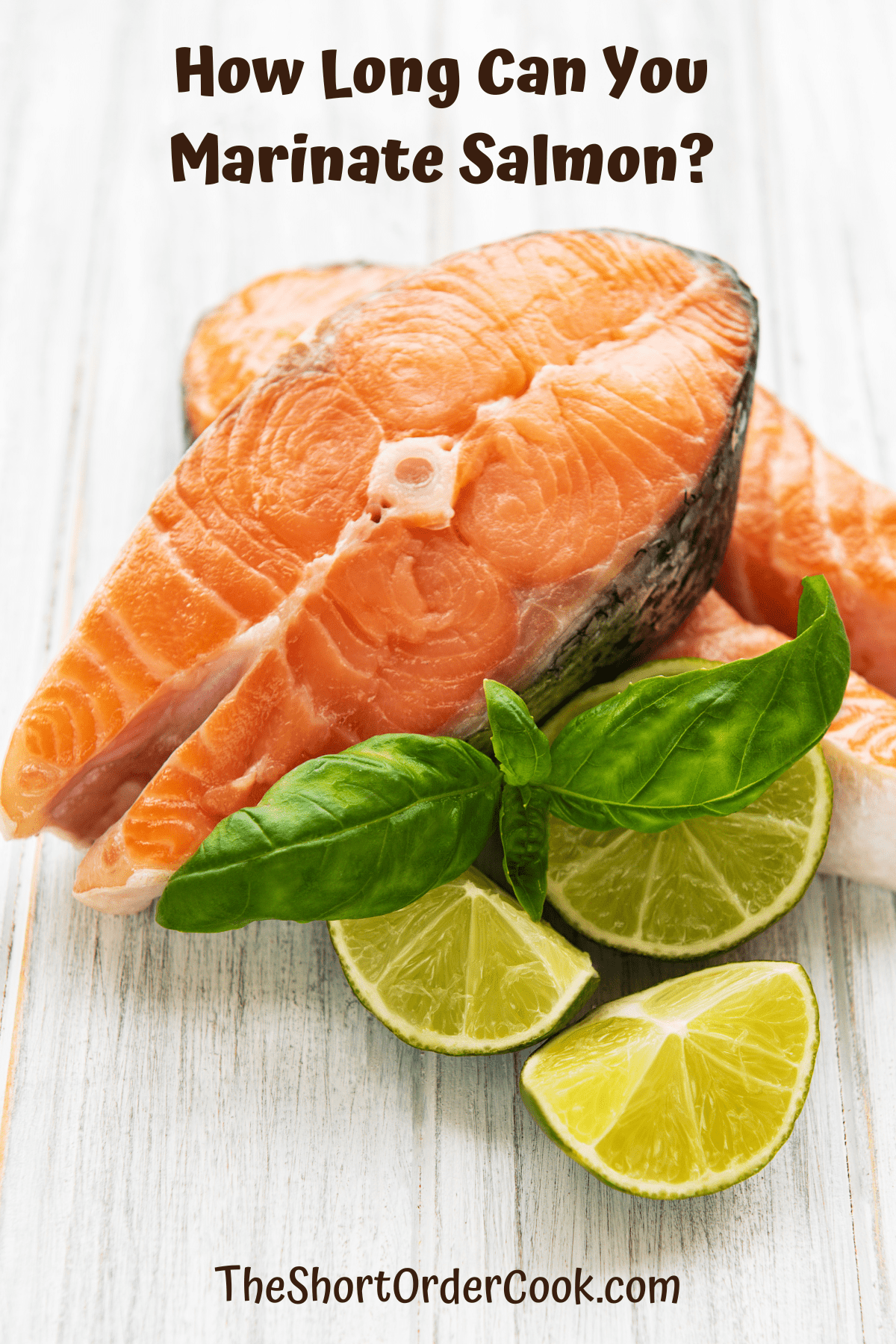 Salmon steaks on a cutting board with limes and herbs.