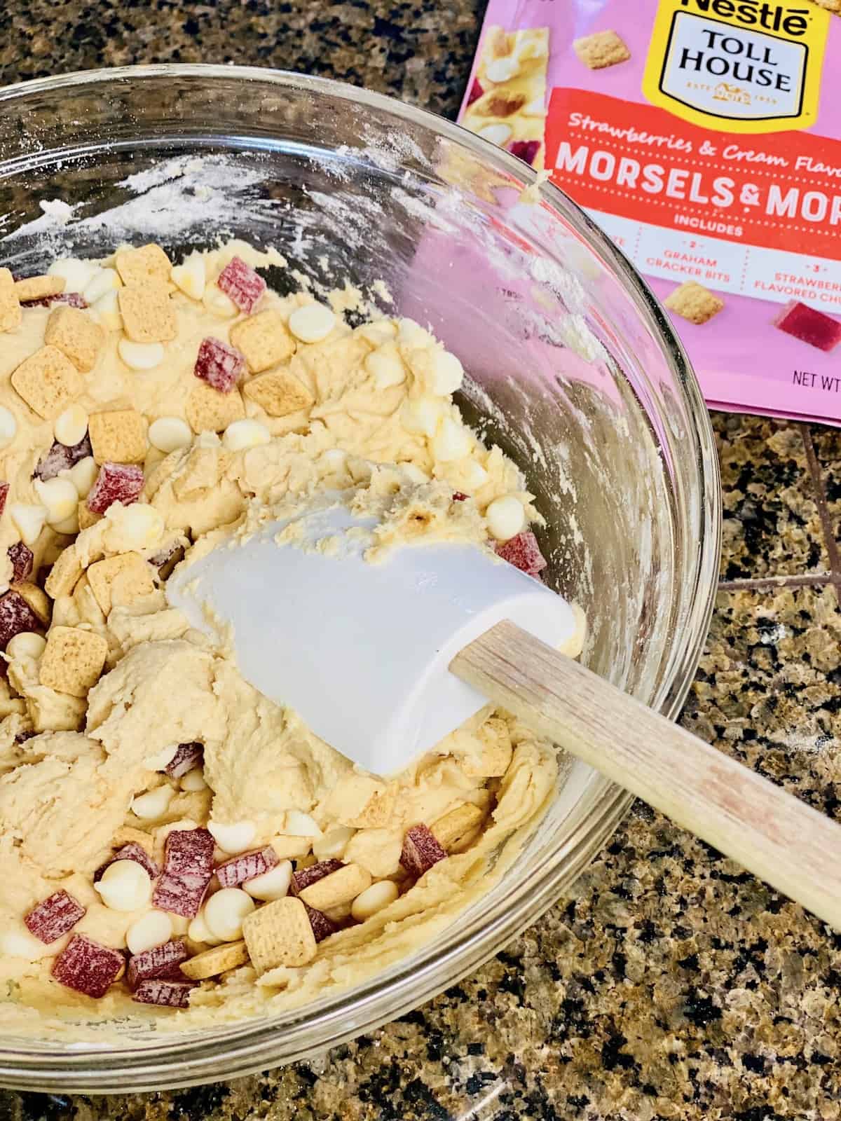 Bowl with the cookie dough ready and the Morsels and more strawberries and cream pieces being stirred in.
