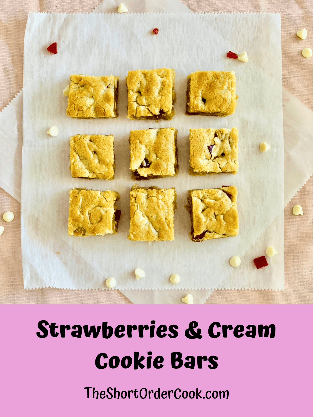 Squares of strawberries and cream cookie bars lined up on parchment paper.