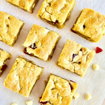 Strawberries & Cream Cookie Bars Recipe card overhead of cut square bar cookies on white parchment.