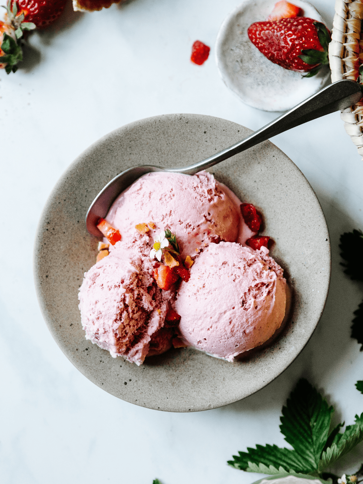 strawberry ice cream topped with fresh berries and mint leaves.