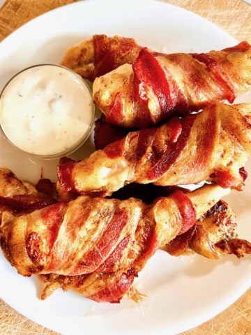White plate with crispy bacon-wrapped chicken tenders.