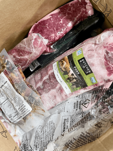 Inside the ButcherBox delivery box with frozen sealed packages of meat.