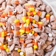 A bowl of puppy chow with candy corns.