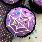 Purple frosted cupcake with a white frosting spiderweb design.