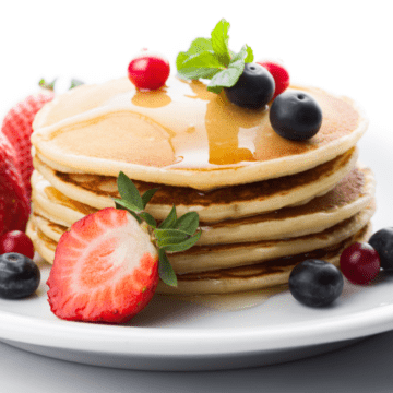 Stack of pancakes with syrup and fresh fruit.
