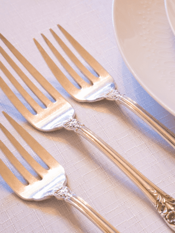 Salad, dinner, and dessert fork placed left to right next to a plate.