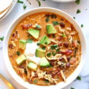 A big bowl of creamy chicken taco soup topped with avocado and sour cream.