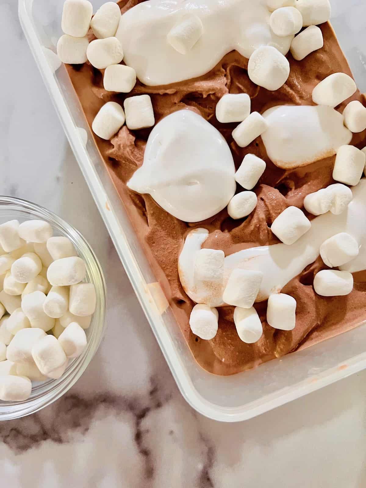 Marshmallows on top of the chocolate ice cream ready to mix in.