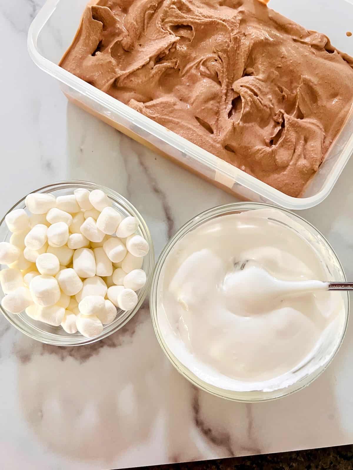 Chocolate Marshmallow Ice Cream ready in a container with marshmallow minis and fluff ready to stir in.