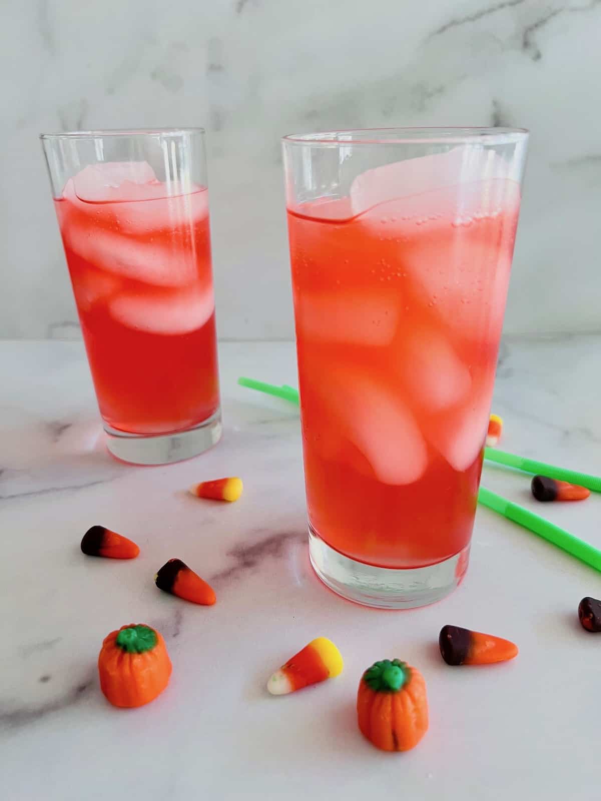 Two glasses filled and straws on the table with Halloween candies