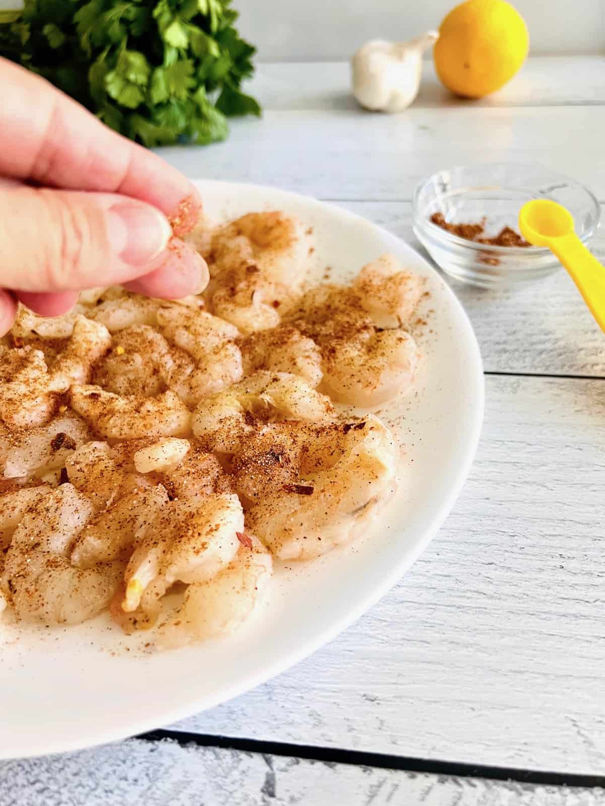 Sprinkling seasonings on shrimp.