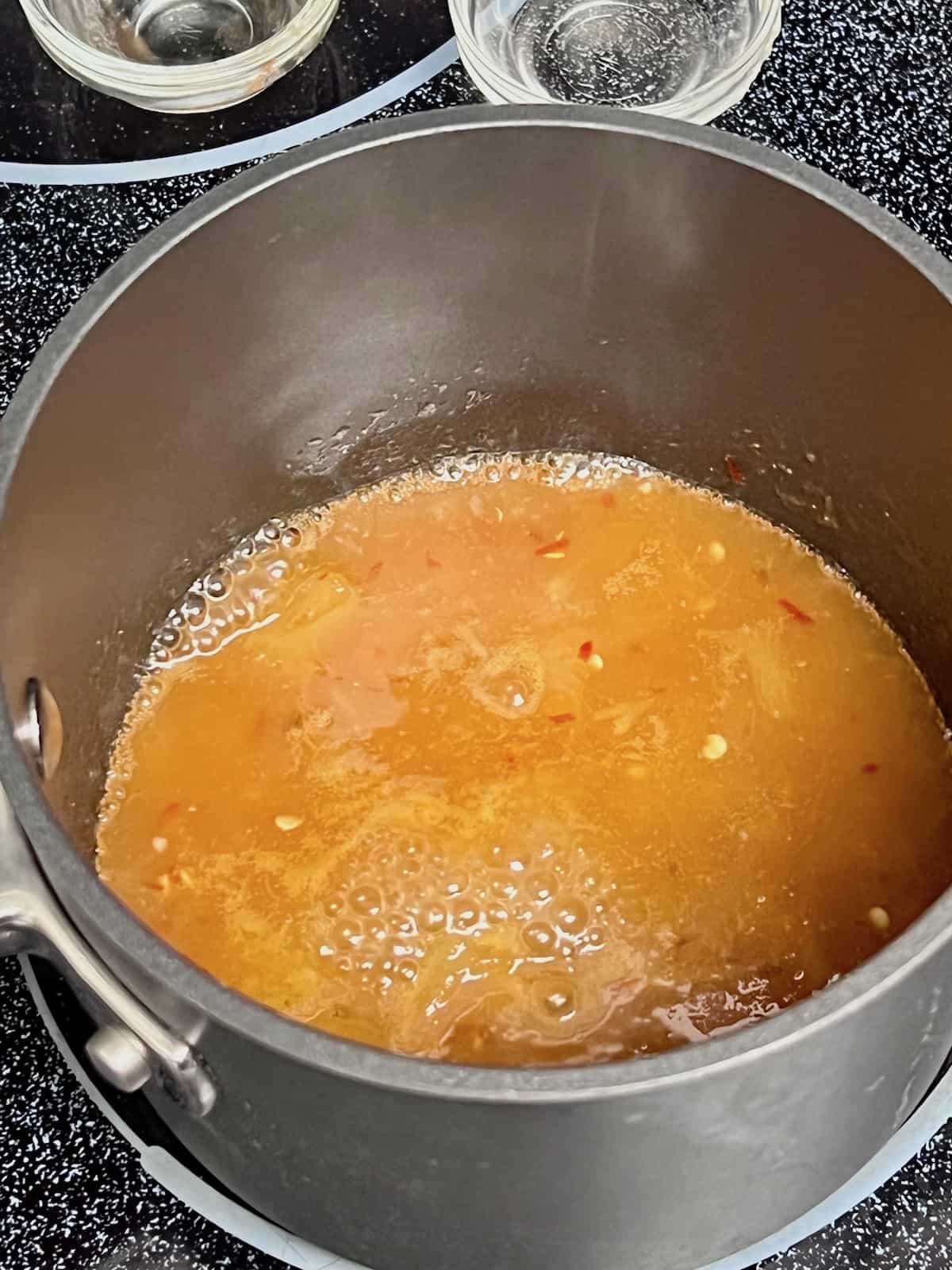 Pineapple Dipping Sauce for Coconut Shrimp bubbling in a pot.