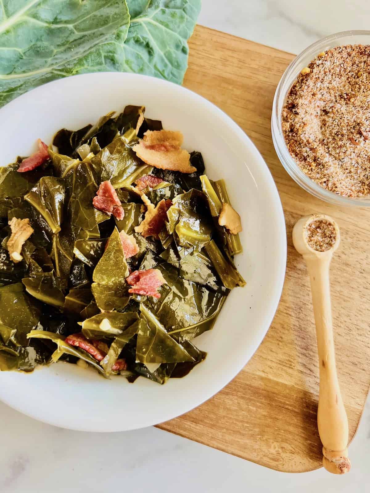 Slow Cooker Collard Greens Cooked greens in a bowl on a wooden cutting board.