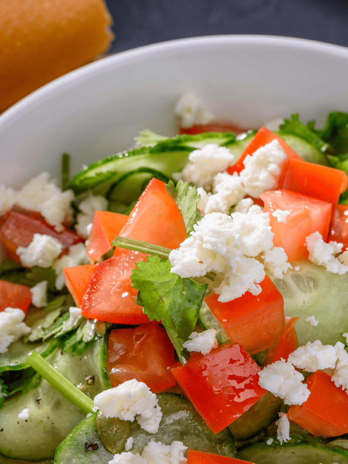 Cucumber and tomato salad topped with herbs.