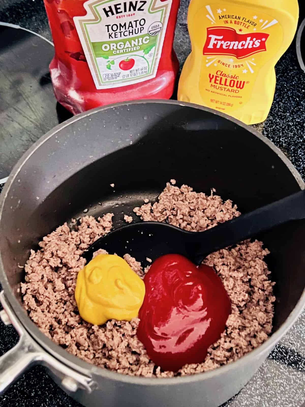 Ground beef in a pot with ketchup and mustard added to make 3-ingredient sloppy joes.