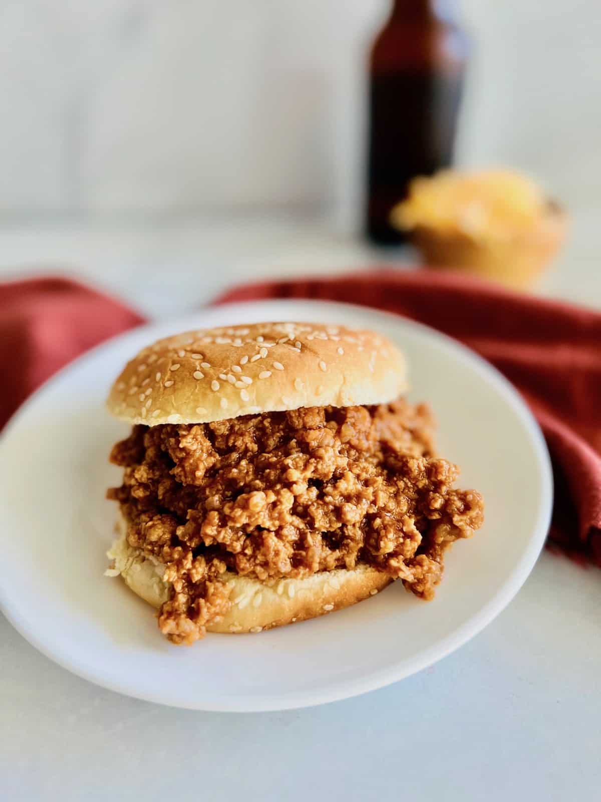3-ingredient sloppy joe plated with a beer and a bowl of cheese in the background.