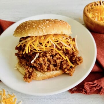 Sloppy joe meat on a bun with cheese plated and ready to eat.