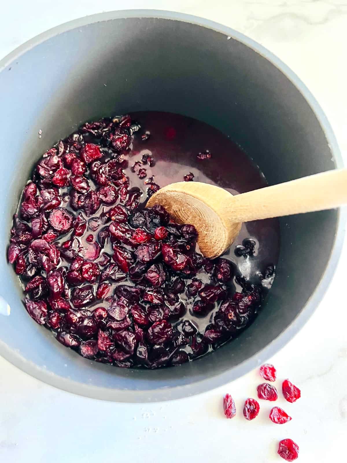 All the ingredients to make cranberry sauce from dried cranberries in a pot ready to cook.