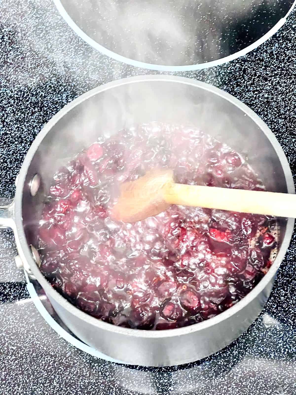 Cranberry Sauce from Dried Cranberries Dried cranberries and ingredients boiling in a pot on the stove..