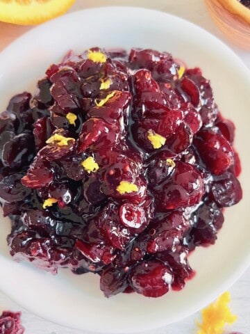 Cranberry Sauce from Dried Cranberries featured overhead in white bowl topped with orange zest.