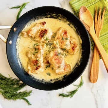 Creamy lemon and dill butter sauce over chicken thighs in a skillet.