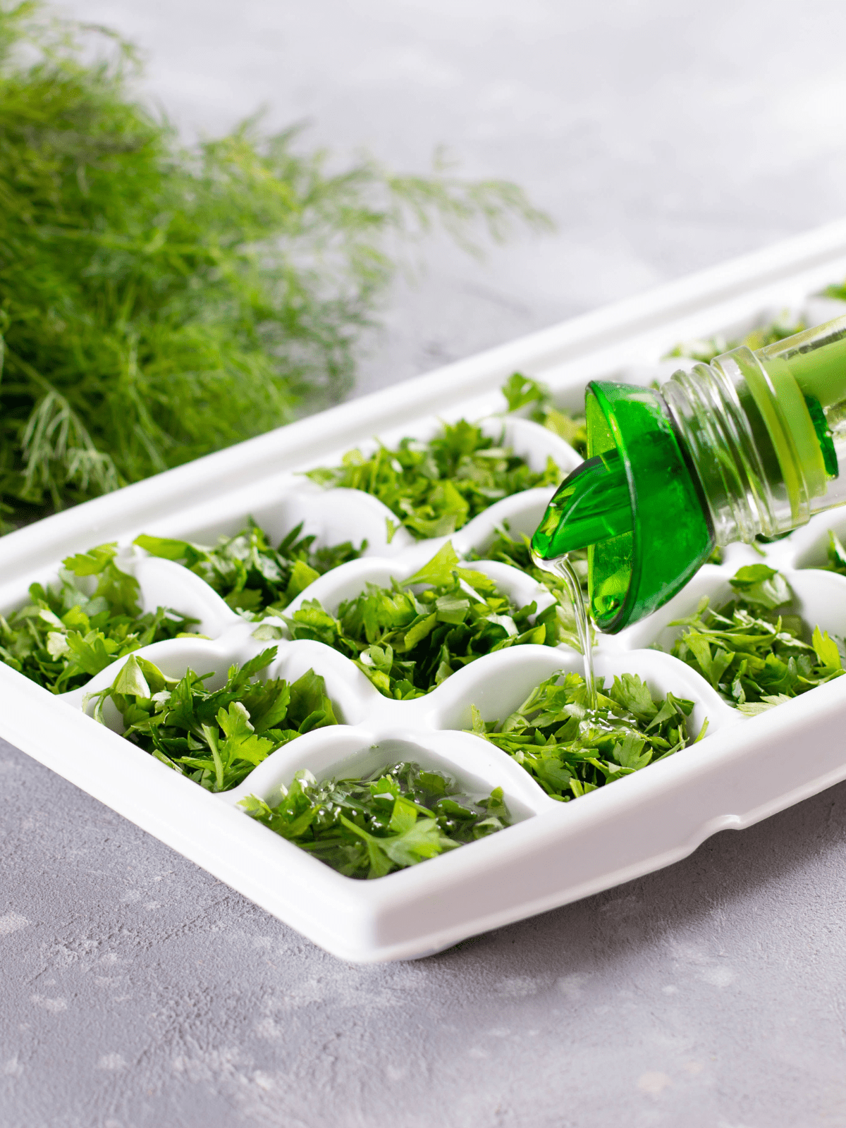 Freezing herbs in an ice cube tray with olive oil. 