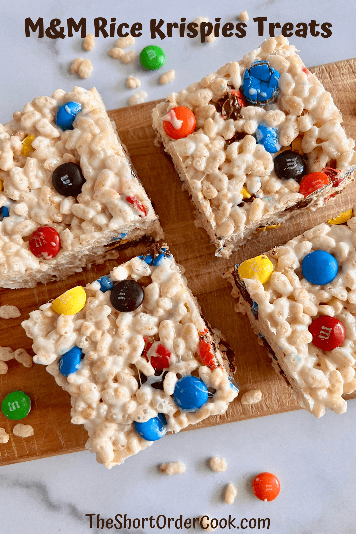 Squares of rice krispie treats with MM&Ms on a board.