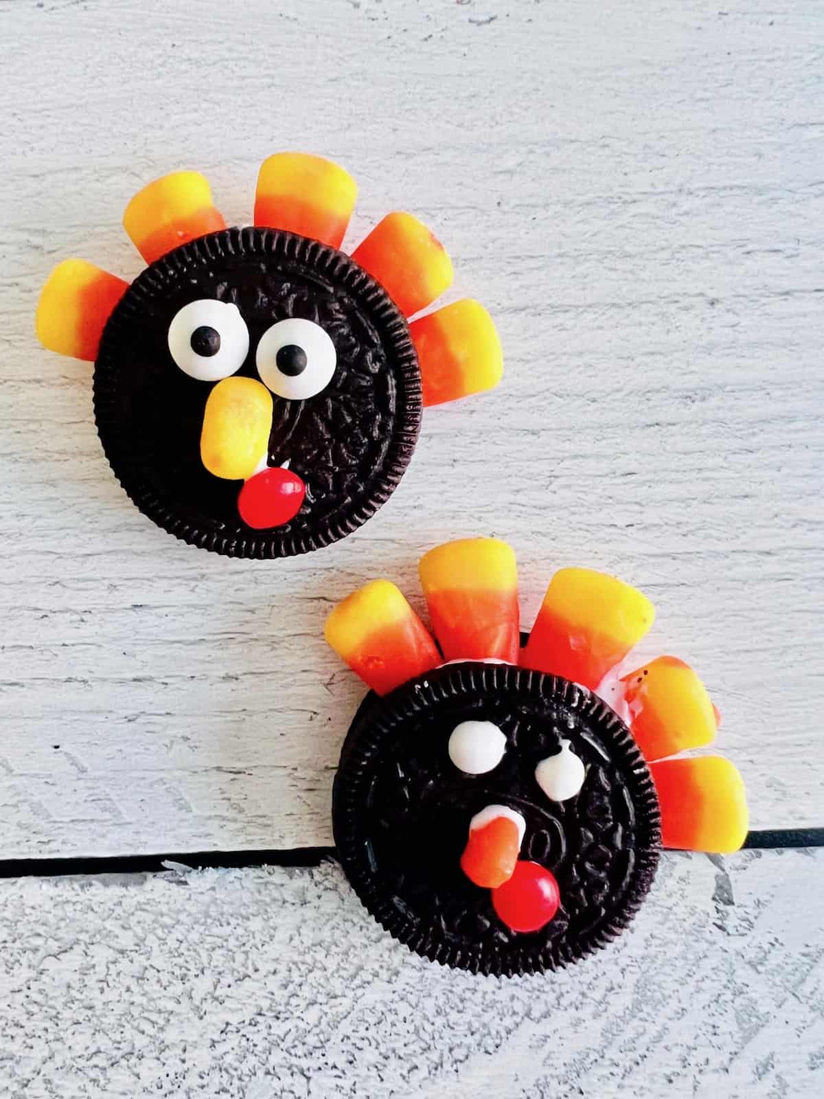 Two turkey faces on Oreo cookies with candy corn feathers between the cookie layers.