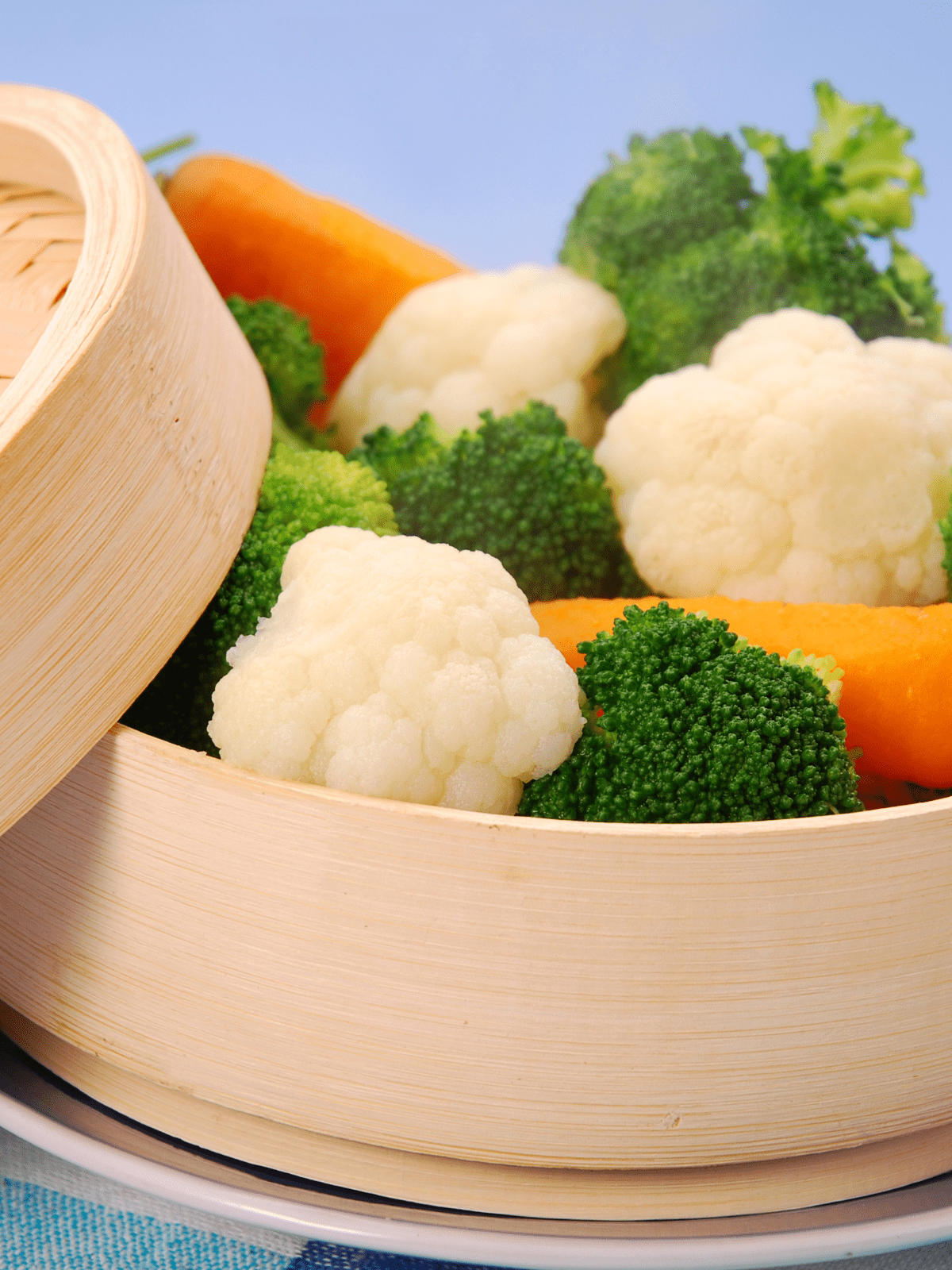 Steamed Frozen Vegetables Bamboo steamer with broccoli and carrots and cauliflower steaming.
