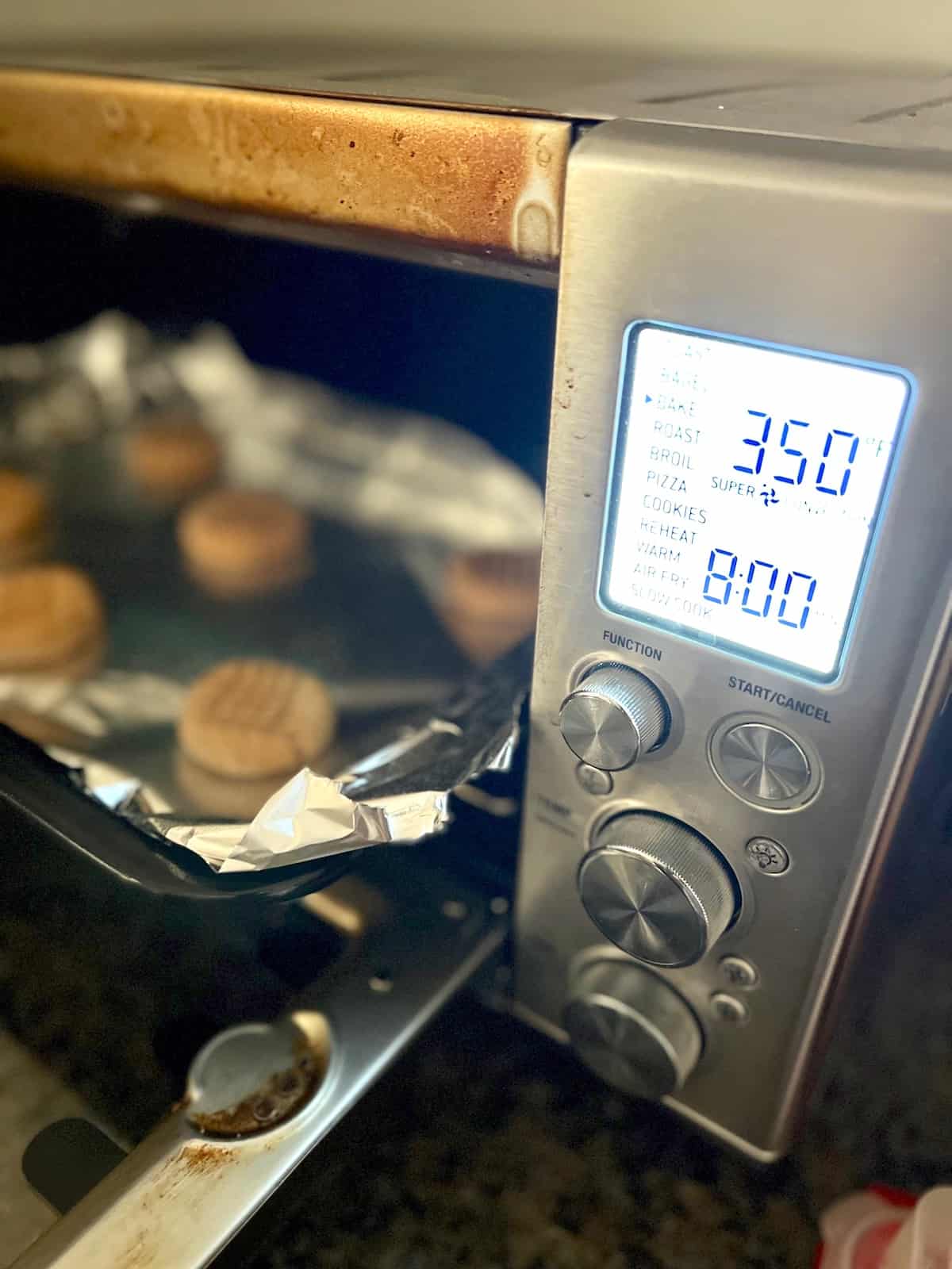 Tray of cookies in toaster oven with time and temp set.
