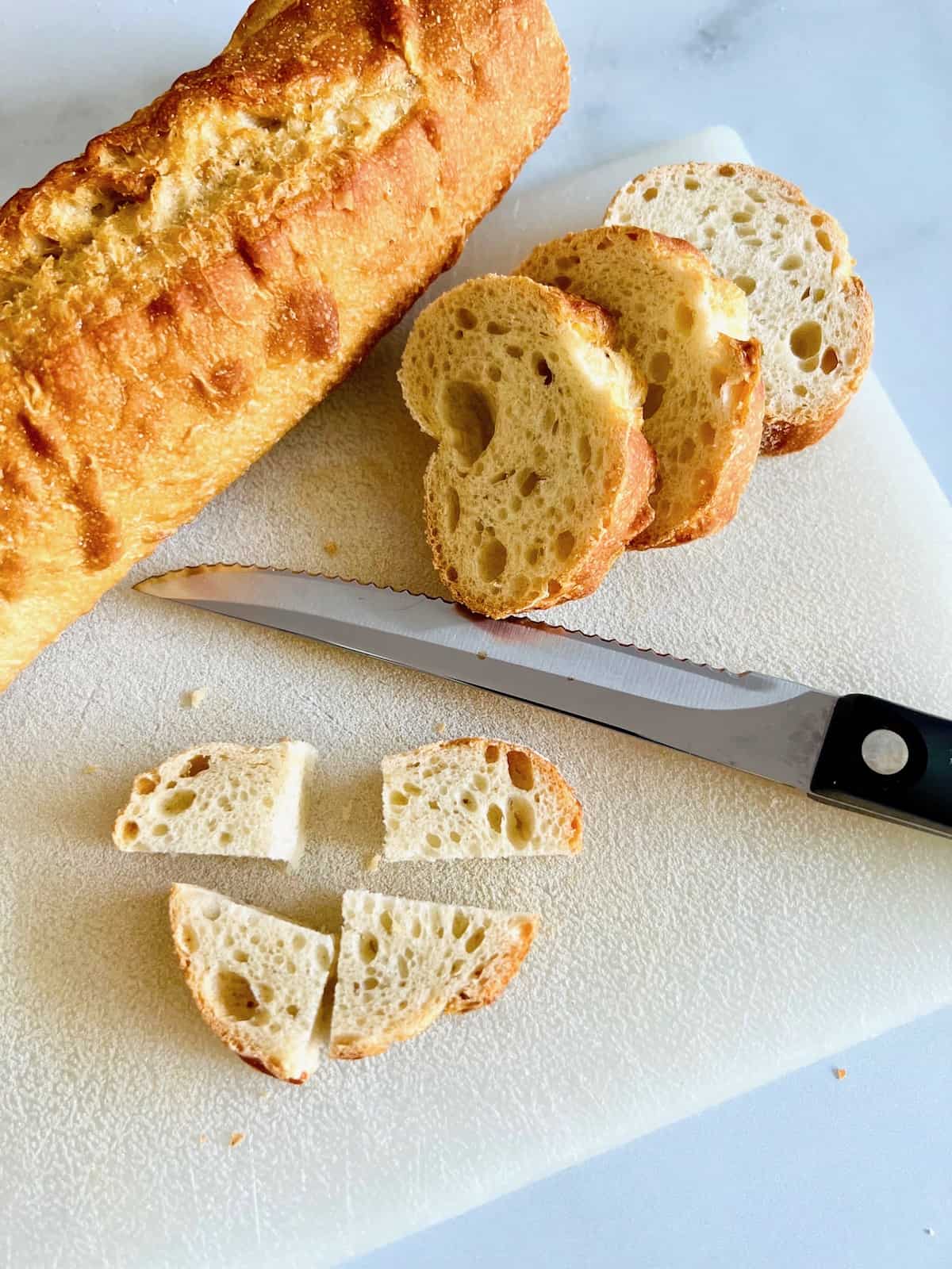 Cutting the bread into cubes on the board to be bite-size.