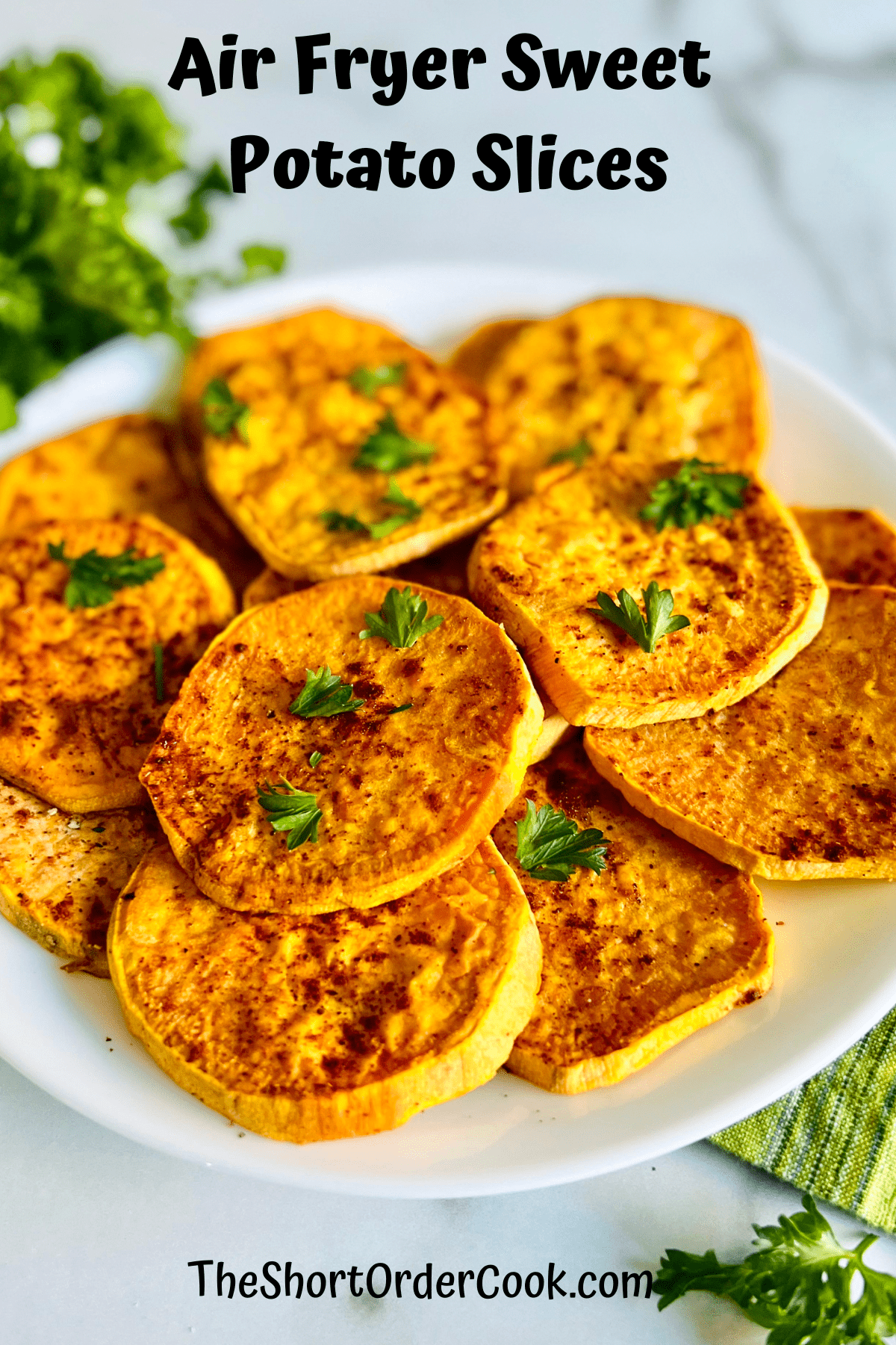 Plate of sweet potato slices cooked in the air fryer and topped with fresh parsley.