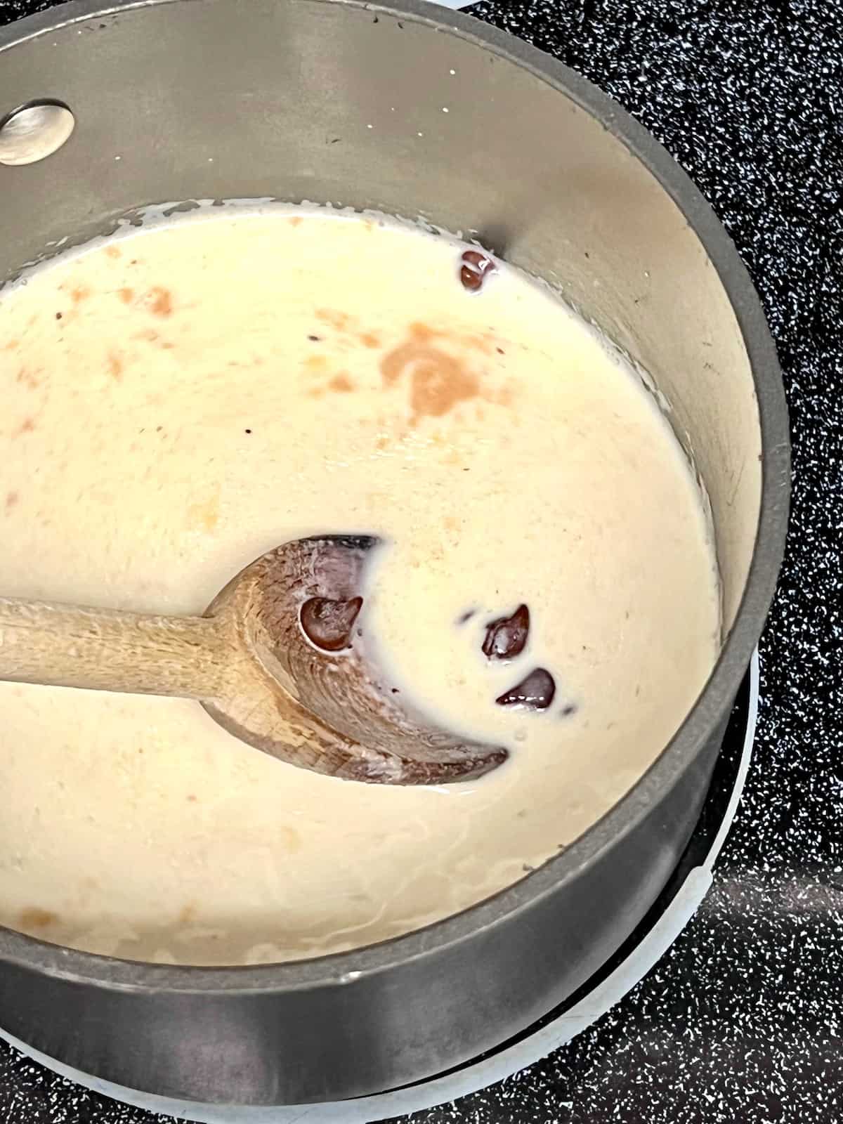 Chocolate being stirred into warm cream.